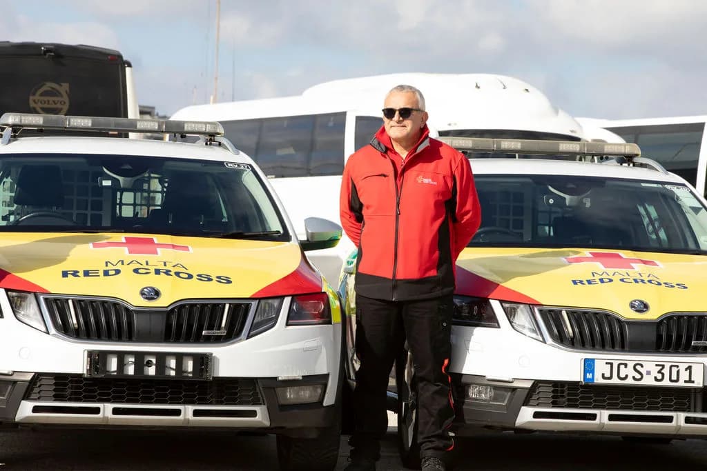Malta Red Cross responder standing between marked emergency response vehicles
